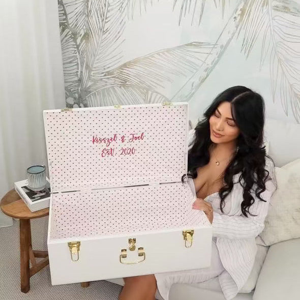 Woman sitting on a couch with a personalized white suitcase and polka dot cover.