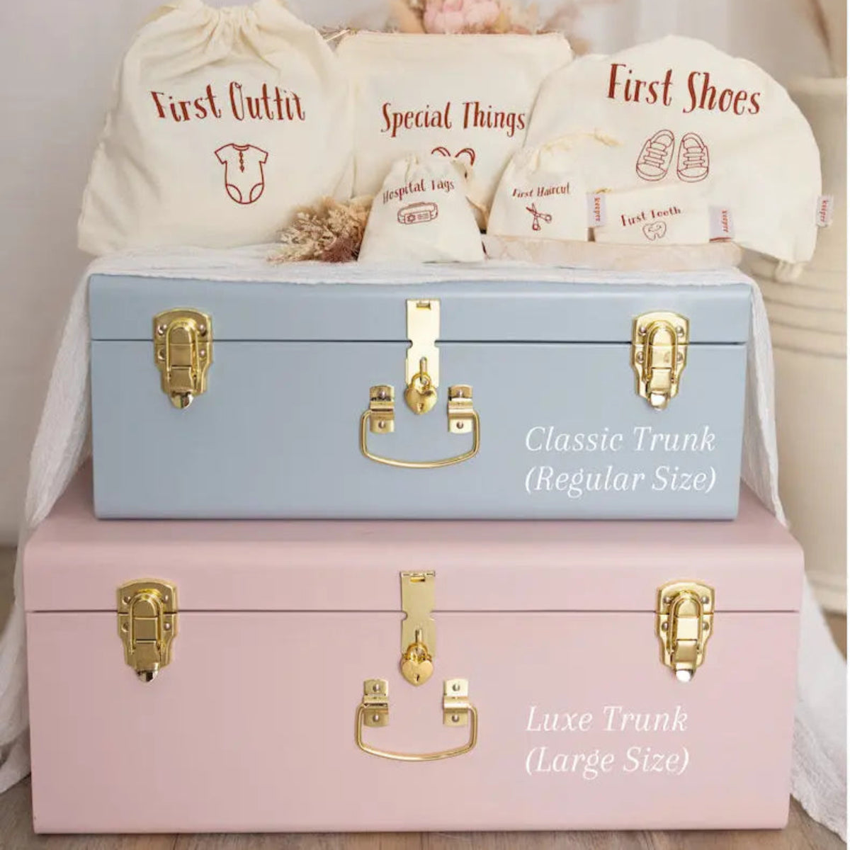 Two trunks, one blue and one pink, with baby items and bags on a light background.