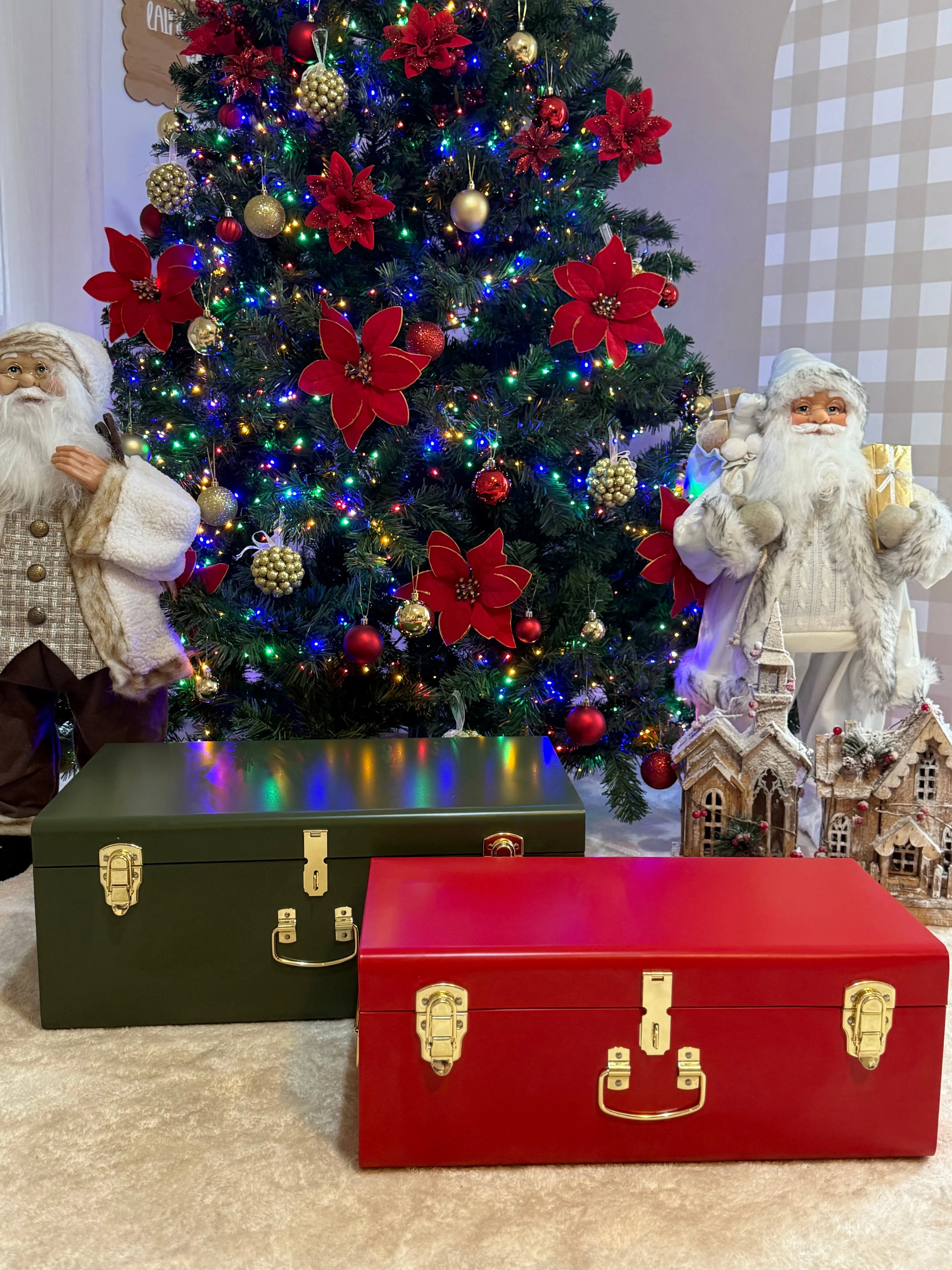 Two vintage-style trunks in front of a decorated Christmas tree with Santa figures.