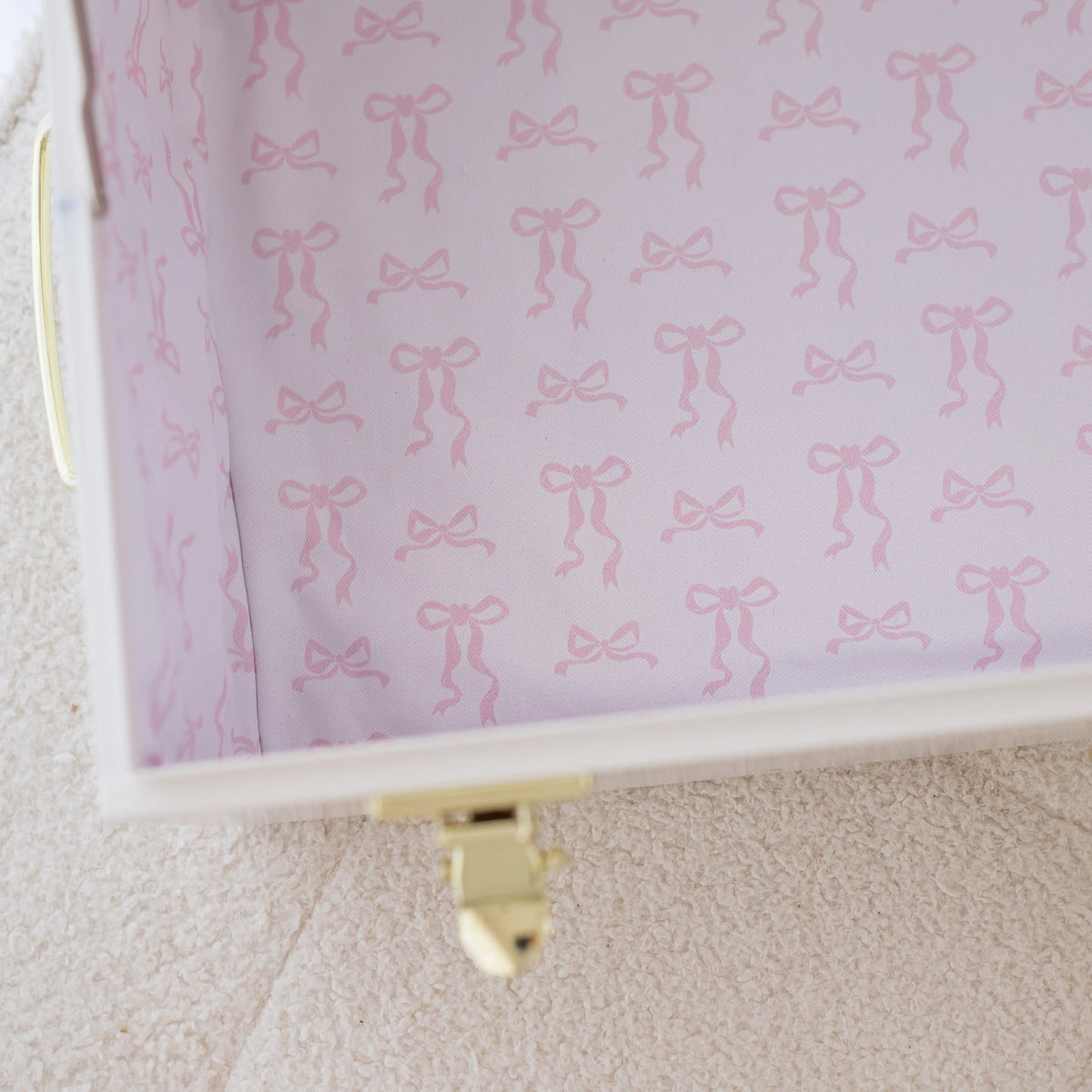 Pink jewelry box with bow pattern on a beige surface