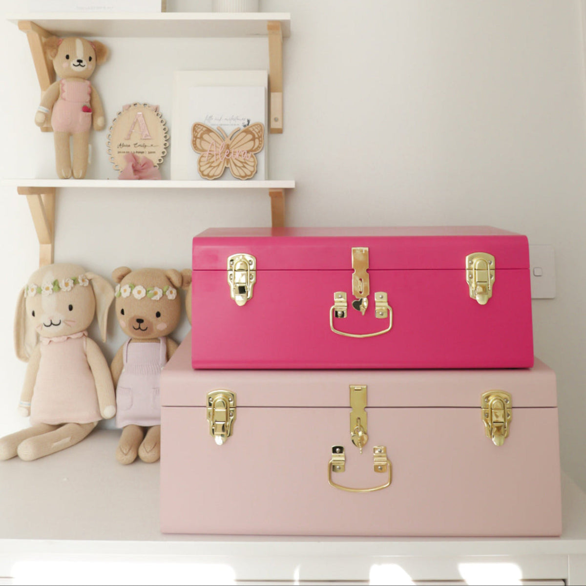 Pink and gold trunks on a white surface with shelves in the background