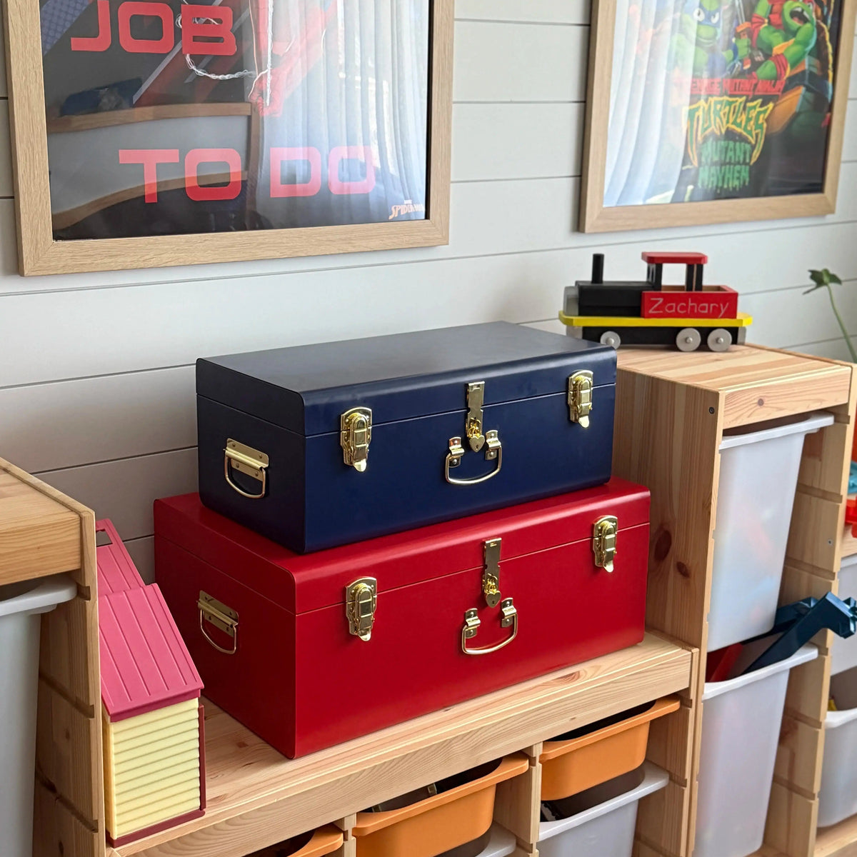 Colorful storage bins on a wooden shelf with framed artwork on the wall.