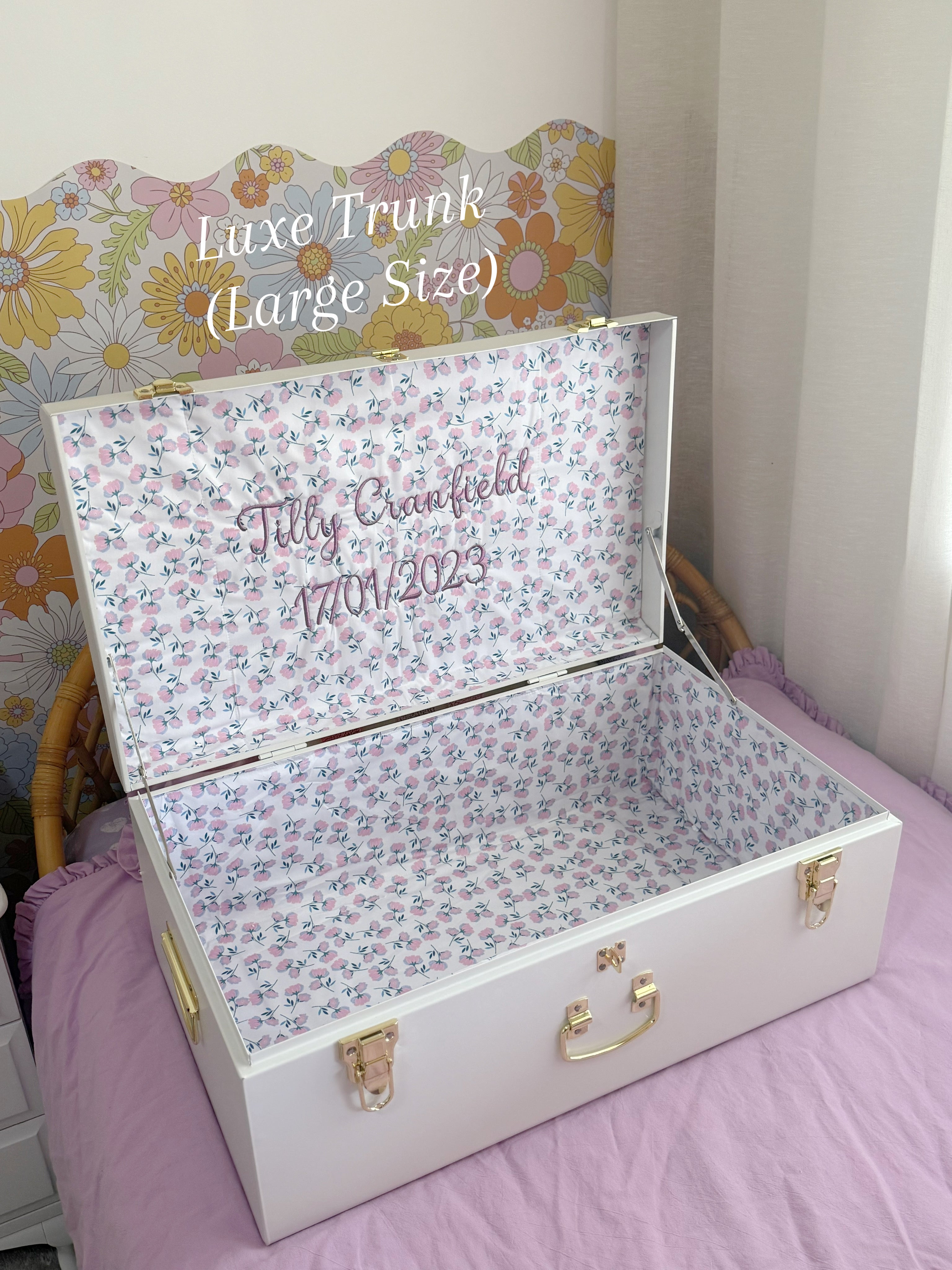Floral-patterned trunk with personalized text on a bed