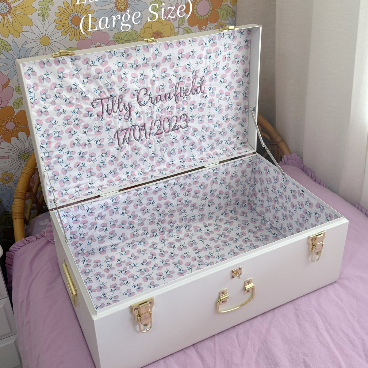 Floral-patterned trunk with personalized text on a bed