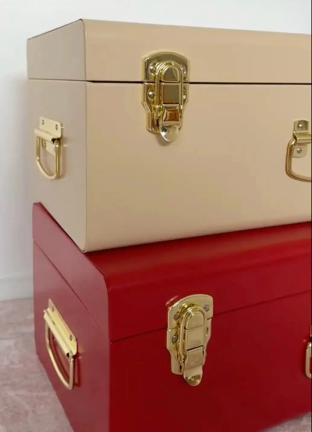Two stacked boxes, one beige and one red, with gold latches on a light background.