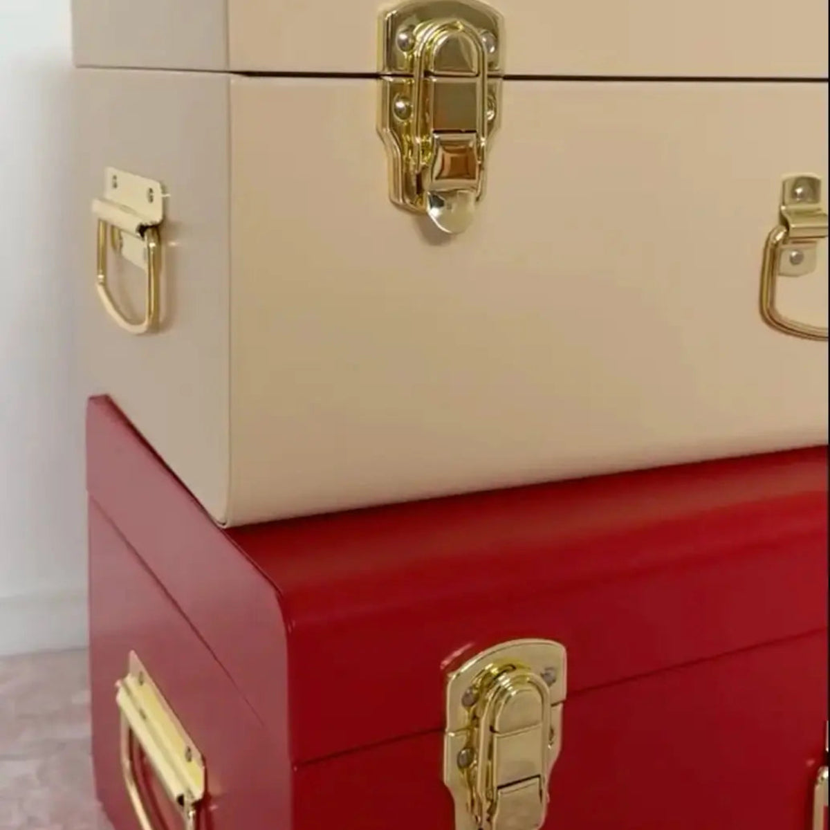 Two stacked boxes, one beige and one red, with gold latches on a light background.