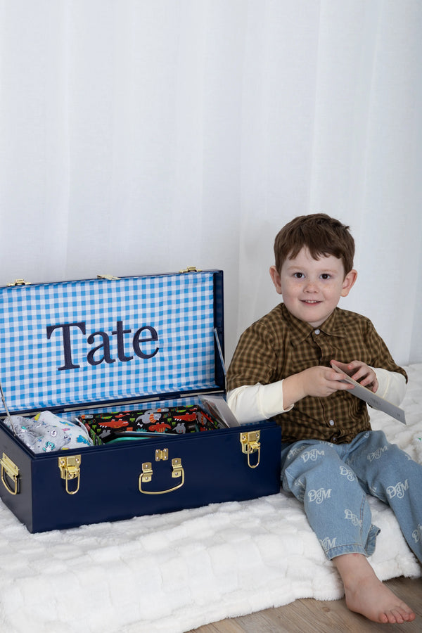 Child with a suitcase labeled 'Tate' on a white background