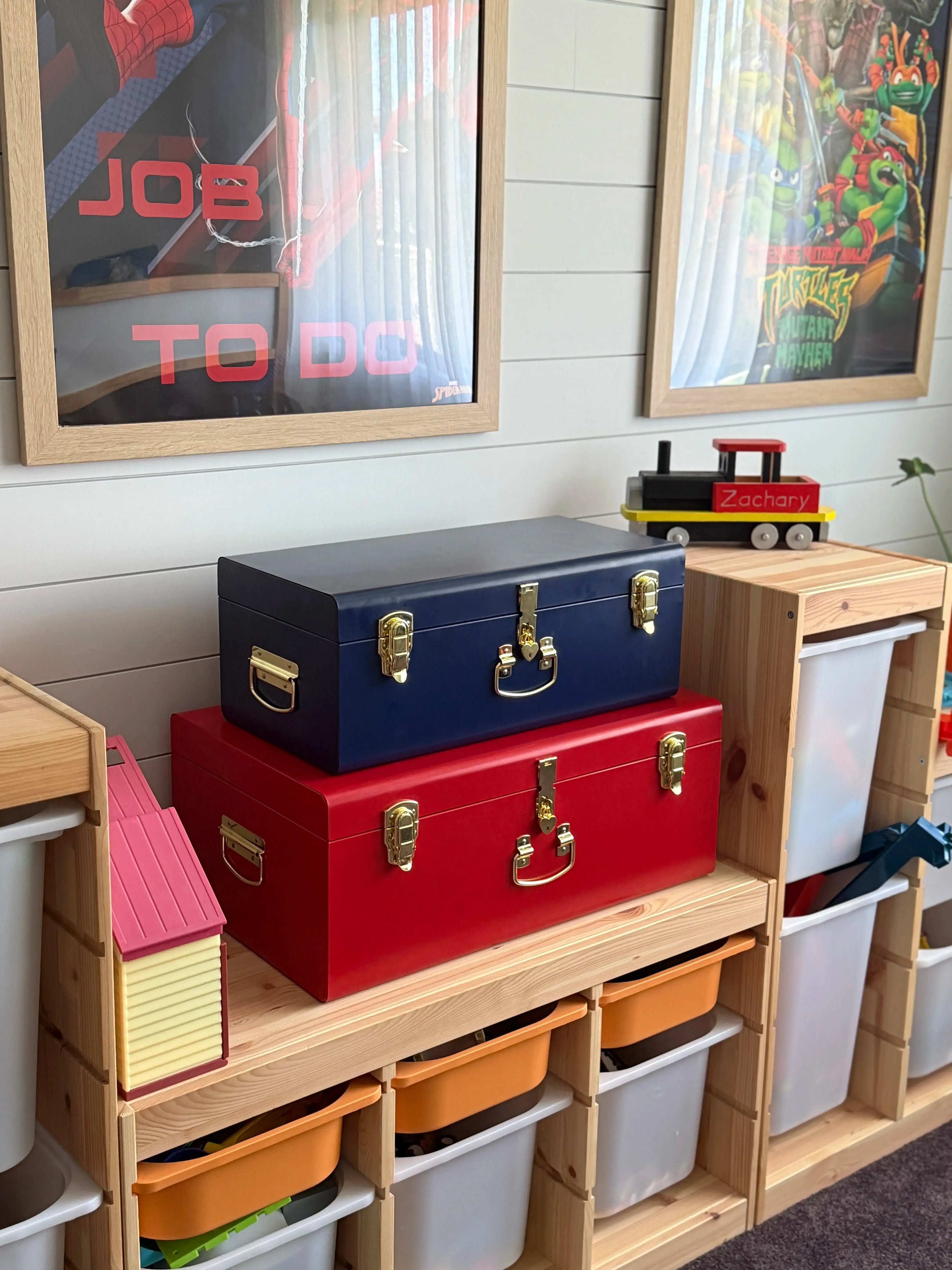 Colorful storage bins on a wooden shelf with framed artwork on the wall.